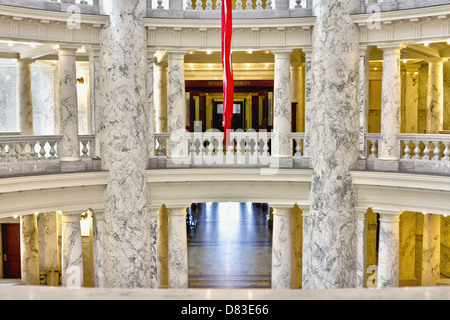 Symmetrische Ansicht von Marmorsäulen im Inneren des Idaho State Capitol Gebäude mit amerikanischer Flagge hängt im Zentrum Stockfoto