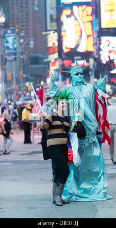 Ein Tourist auf dem Times Square hat ihr Foto mit einem Mann, gekleidet wie die Statue of Liberty. Stockfoto