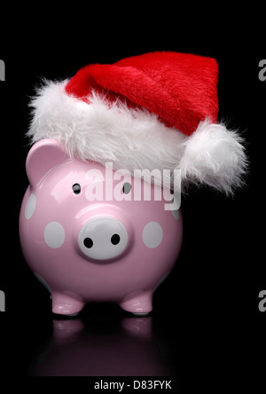 Piggy Bank in Weihnachtsmütze auf schwarzem Hintergrund isoliert Stockfoto