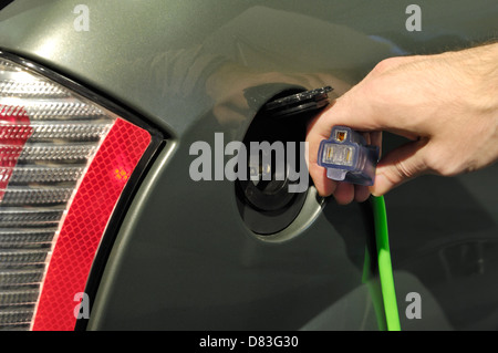 Nahaufnahme von einer Person, die einen Netzkabel in der Nähe einer Batterie-Steckdose der ZENN ein Plugin Elektroauto Stockfoto