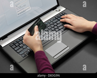 Frau an einem Laptop sitzen und ihre Kreditkarten-Informationen in ein Onlineformular eingeben Stockfoto
