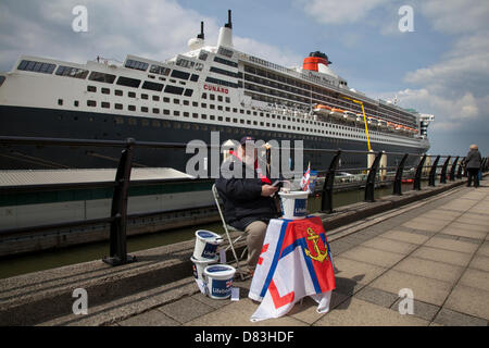 Liverpool, Großbritannien, 17. Mai, 2013. Ray Roberts, von Edgehill sammeln für rnli Küstenwache Nächstenliebe an der Cruise Liner Terminal, wo der Liner RMS Queen Mary 2 bei ihrem Besuch in der Stadt Anker. Der Liverpool Cruise Terminal ist eine 350 Meter lange schwimmende Struktur liegt am Fluss Mersey, die großen Kreuzfahrtschiffe, ohne die mitgelieferte Dock System oder liegestelle Mitte - Fluss- und Ausschreibungsverfahren Passagiere an Land zu besuchen. Das Terminal wurde offiziell am 21. September 2007 von Seiner Königlichen Hoheit, dem Herzog von Kent, wenn die Queen Elizabeth 2 am Terminal im Hafen eröffnet. Stockfoto