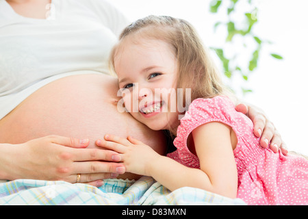 Kind Mädchen hören Bauch der schwangeren Mutter Stockfoto