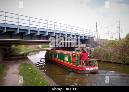 Schmale Boot unter Eisenbahnbrücke hindurch auf dem Trent und Mersey Kanal in der Nähe von Sandbach Cheshire UK Stockfoto