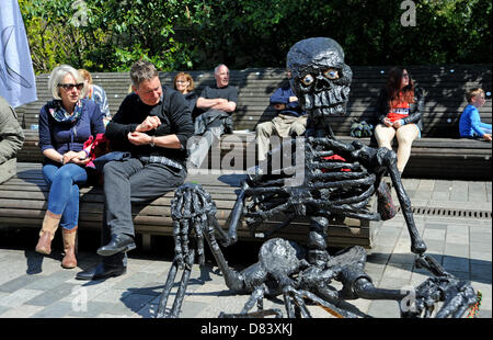 Brighton UK sitzt 18. Mai 2013 - eine seltsame schwarze Totenkopf und Skelett Figur neben Menschen auf einer Bank an der Fringe-City-Event ist Teil der Brighton Festival 2013 Stockfoto