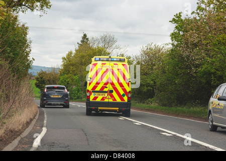 Blick durch eine Windschutzscheibe und ein Krankenwagen mit Blaulicht zu einem Notfall überholen ein Auto entlang einer Hauptstraße zu hetzen. Shropshire England Großbritannien Stockfoto