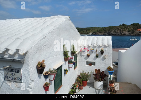 Weiß getünchten Häuschen mit Flachdachziegel Dach und Blumentöpfe auf Wand. Es Grau, Menorca, Balearen, Spanien Stockfoto