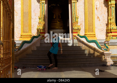 PHUKET, THAILAND 15. Mai 2013: Frau legt Schuhe wieder auf nach dem Besuch der Stupa im Wat Chalong Stockfoto