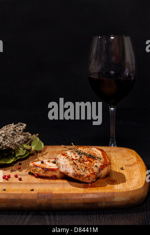 Gegrilltes Steak mit Glas Rotwein auf dunklem Hintergrund Stockfoto