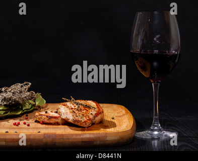 Gegrilltes Steak mit Glas Rotwein auf dunklem Hintergrund Stockfoto