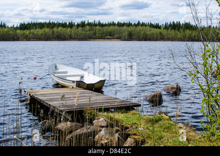 Kleines Ruderboot an einem alten Pier in einem See im Wald. Aus der Provinz Småland in Schweden. Stockfoto