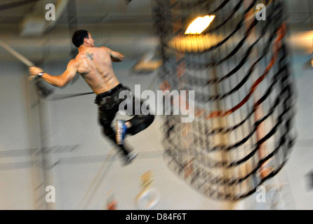 Ein Kandidat der US Navy SEAL schwingt auf einer erhöhten Gepäcknetz an einem erhöhten Parcours Naval Special Warfare 11. Mai 2013 in Little Creek, VA. SEAL Kandidaten nutzen den Hindernis-Parcours in der Vorbereitung für die Teilnahme an der Basic Underwater Demolition/SEAL-Kurs. Stockfoto