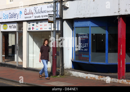 Junger Mann zu Fuß vorbei an leerstehenden Läden während der Rezession in Camden Road, Tunbridge Wells, Kent, England Stockfoto