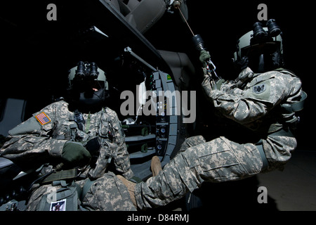 Truppführer sitzt in der Tür ein UH-60 Black Hawk Medevac-Hubschrauber während der Medic auf der Hebebühne steht sitzt. Stockfoto