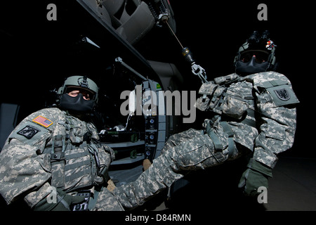 Truppführer sitzt in der Tür ein UH-60 Black Hawk Medevac-Hubschrauber während der Medic auf der Hebebühne steht sitzt. Stockfoto