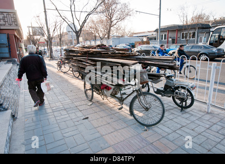 Fahrrad beladen mit alten Dielen und Holz auf Bürgersteig in Peking, China Stockfoto