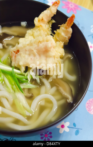 Udon-Nudeln mit Garnelen-Tempura in schwarz Schüssel, japanisches Essen Nahaufnahme Stockfoto