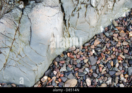 Kleiner Strand Steinen gewaschen gegen eine glatte zu Tage tretenden Stein Welle getragen. Stockfoto