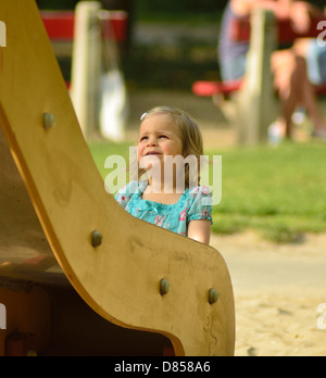 2 Jahre altes Mädchen beobachten eine große Rutsche am Spielplatz Stockfoto