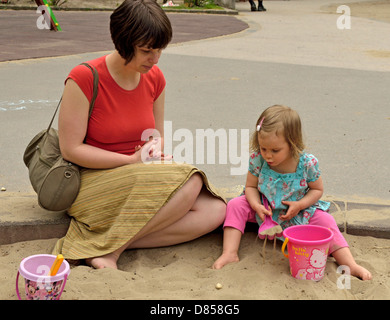 2 Jahre altes Mädchen mit Mutter im Sandkasten spielen Spielzeug Spielplatz Stockfoto