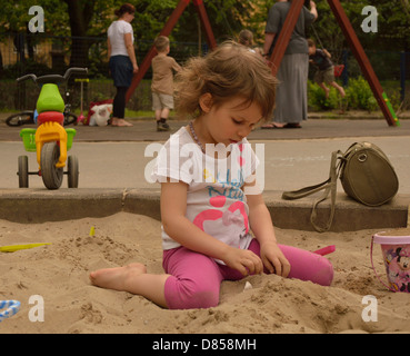 Kleine Mädchen spielen im Sand am Spielplatz Stockfoto