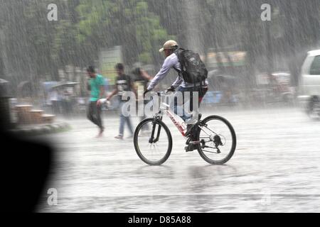 Dhaka, Bangladesch. 10. Mai 2013. Ein Bangladeshi Student fährt mit dem Fahrrad im Regen in der Universität von Dhaka, Dhaka, Bangladesh, 20. Mai 2013. Stadtbewohner haben einige Erleichterung nach dem Duschen, während niedrig liegenden Straßen waren durch eine halbe Stunde unter Wasser in vielen Bereichen in der Hauptstadt zu gießen. Stockfoto