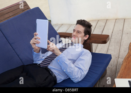 Geschäftsmann am Sofwith digital-Tablette liegen. Stockfoto