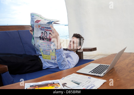 Geschäftsmann am Sofreading Zeitung liegen. Stockfoto