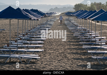 Leeren Strand Sonnenliegen mit einsame männliche Figur in der Ferne Rethymna Beach Kreta Stockfoto