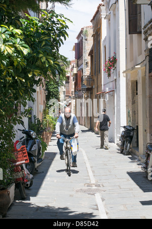 Ein Mann-Zyklen entlang einer schmalen Straße innerhalb der alten Stadt Rethymnon, Crete. Stockfoto