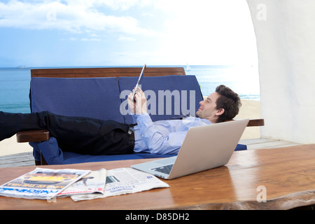 Geschäftsmann am Soflooking digital-Tablette liegen. Stockfoto