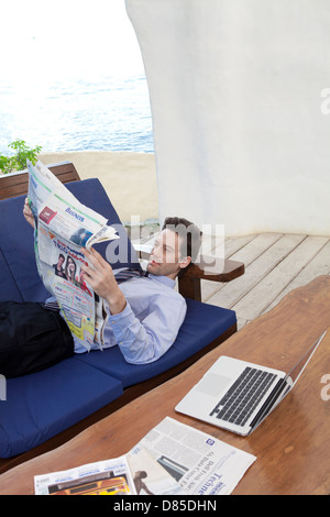 Geschäftsmann am Sofreading Zeitung liegen. Stockfoto