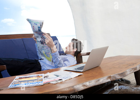 Geschäftsmann am Sofreading Zeitung liegen. Stockfoto