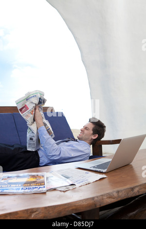 Geschäftsmann am Sofreading Zeitung liegen. Stockfoto