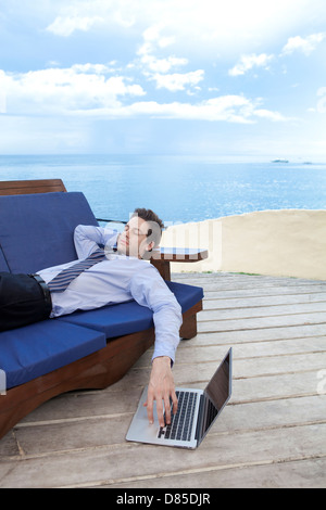 Geschäftsmann am Sofwith Laptop liegen. Stockfoto