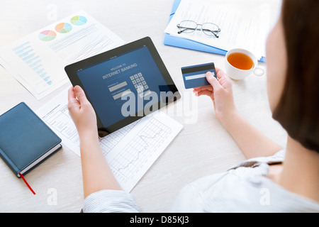 Erfolgreiche Geschäftsfrau, die Eingabe von Login-Daten zur Durchführung von online-Banking-Vorgang auf digitale Tablet im Büro Stockfoto