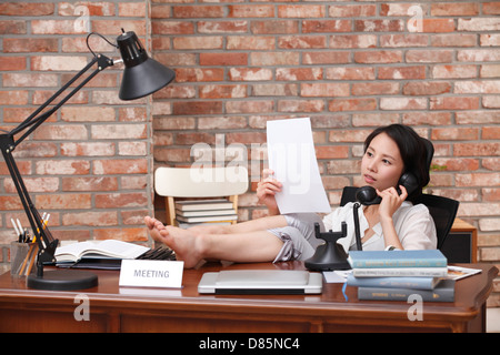 junge Frau sitzen Schreibtisch am Telefon sprechen. Stockfoto