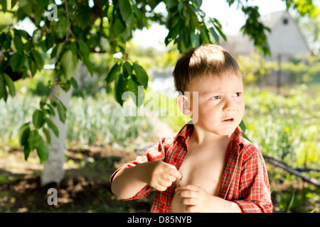 Portrait eines kleinen Jungen spielen im Garten stehen im Sonnenschein suchen Sie auf der rechten Seite des Rahmens Stockfoto