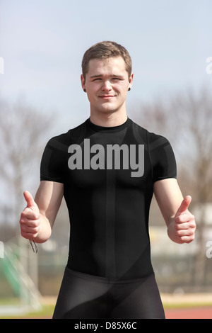 Junge Sportler in einem Stadion steht und Daumen nach oben zeigt Stockfoto
