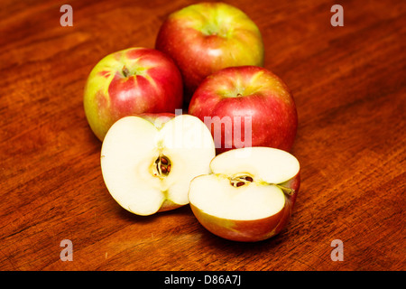 Drei rote und grüne Äpfel auf einem Holztisch mit einem in zwei Hälften geschnitten Stockfoto