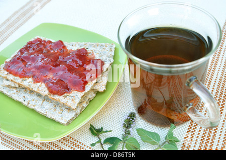 Cracker mit Erdbeermarmelade und Pfefferminztee Stockfoto