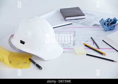 Baupläne, Helm und Stifte auf dem Schreibtisch eines Architekten Stockfoto