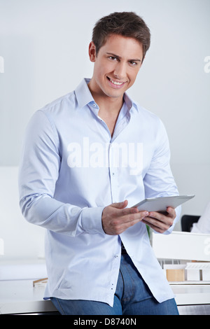 Glücklich lächelnd Geschäftsmann hält einen Tablet-PC im Büro Stockfoto