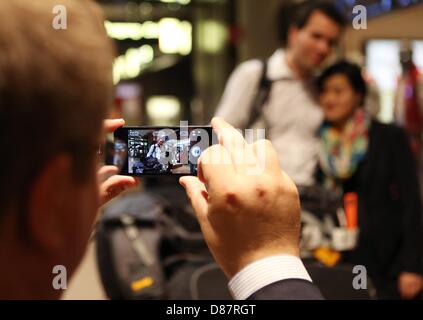 Ein Freund fotografiert Nils Jennrich, Mitarbeiter eines deutschen Kunst-Handling-Unternehmens und seine Verlobte Jenny Damm auf einem Smartphone nach ihrer Ankunft am Flughafen in Hamburg, Deutschland, 21. Mai 2013. Der 32-jährige durfte China verlassen rund 14 Monate nach festgehalten. Er wurde Ende März 2012 unter dem Vorwurf des Zollbetrugs verhaftet. Foto: CHRISTIAN CHARISIUS Stockfoto