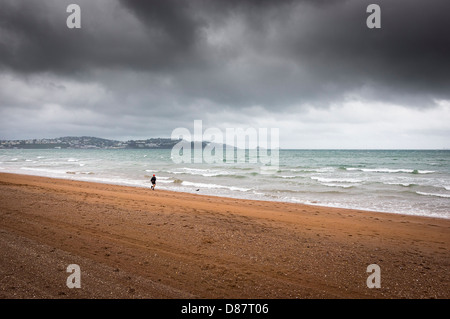 Läufer auf Paignton Beach im Regen mit Gewitterhimmel, Devon Küste, England, UK im Frühjahr/Sommer Stockfoto