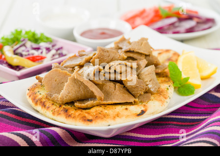 Donner-Fleisch auf Naan - Donner Fleischscheiben auf einem Fladenbrot serviert mit Salat, Chili und Joghurt. Stockfoto
