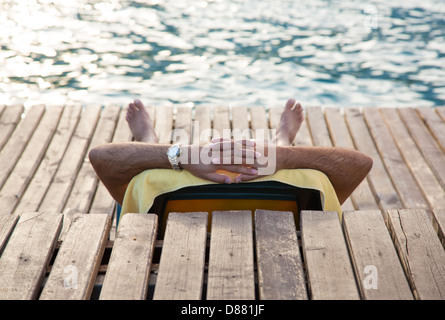 Menschen entspannen Sie sich auf eine Liege zu bekommen während immer eine tan von der Sonne am Meer Stockfoto