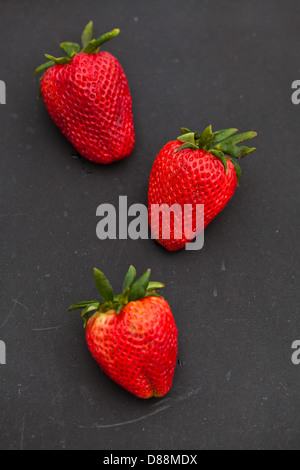 Nahaufnahme von drei großen frischen Erdbeeren vor einem dunklen Hintergrund Stockfoto