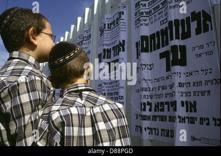 Junge ultraorthodoxe Juden, die Paschkvilim traditionelle Gemeindeankündigungen in Mea Shearim Viertel lesen, einer ultraorthodoxen Enklave in Westjerusalem Israel Stockfoto