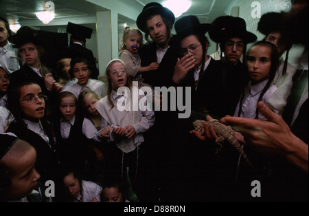 Ein Haredijude, der jungen Kindern in Mea Shearim, einer ultraorthodoxen Enklave in Westjerusalem Israel, eine Echse aus Chamäleons zeigt Stockfoto